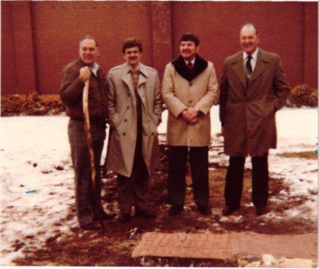 Four men standing outside the museum in winter